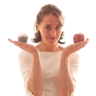 woman holding apple and cupcake